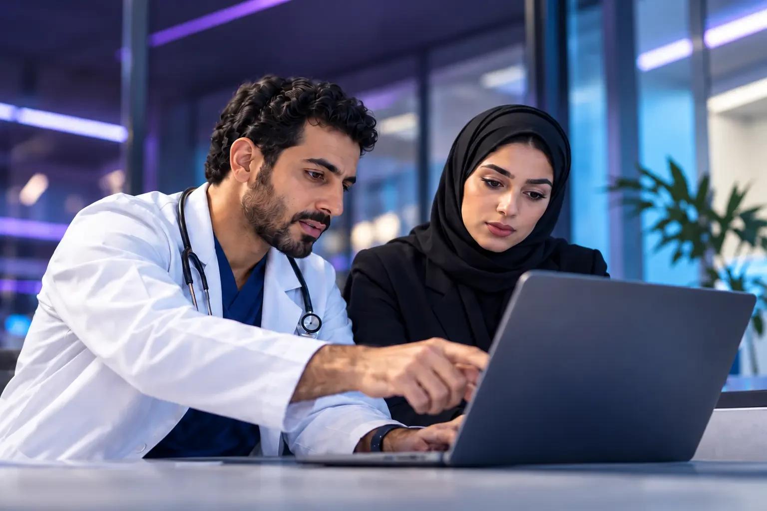 A physician and a colleague reviewing a laptop together